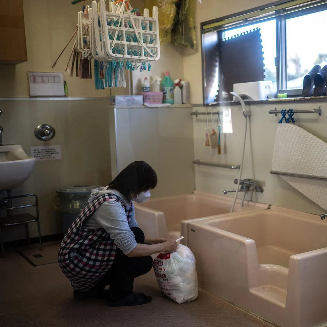 A staff member collects a bag of used diapers at a nursery school in Osaki town, Kagoshima Prefecture, on Jan 16, 2026. 