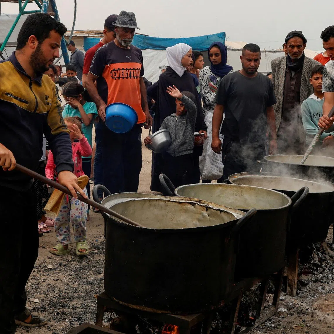 FILE PHOTO: Palestinians gather to receive food cooked by a charity kitchen, in Khan Younis, southern Gaza Strip, April 8, 2025. REUTERS/Hatem Khaled/File Photo