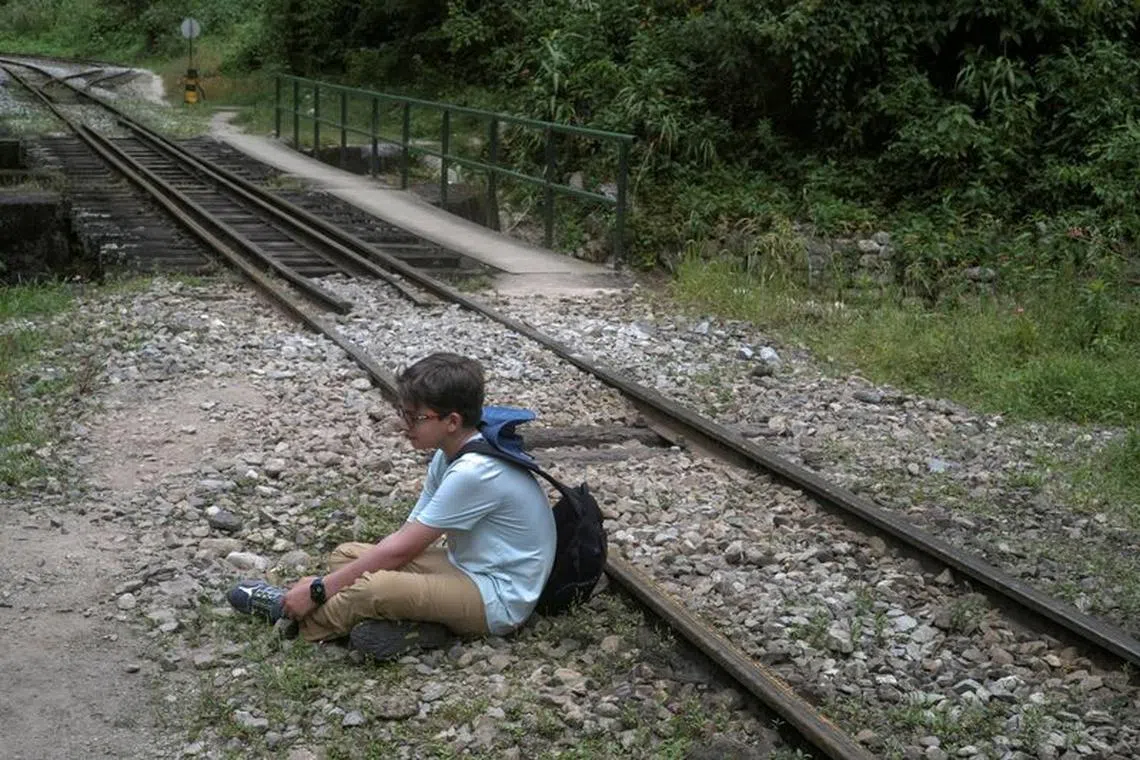 FILE PHOTO: A child traveling with tourists rests next to a train track near the Incan ruins of Machu Picchu, a tourism magnet, access to which is being limited by local protests against rising prices amid a worldwide surge most recently triggered by the Russian invasion of Ukraine, outside of Cuzco, Peru April 18, 2022. Picture taken April 18, 2022. REUTERS/Alessandro Cinque