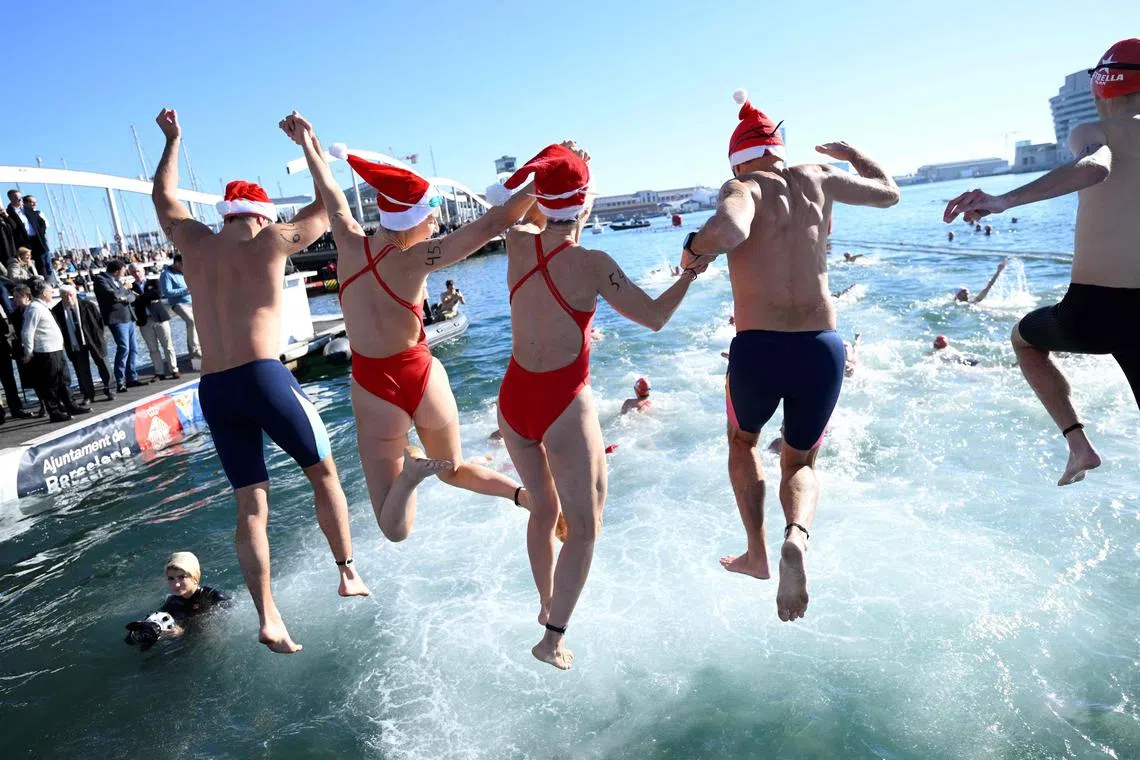 Participants jumping into the water during the 114th edition of the Copa Nadal (Christmas Cup) swimming race in Barcelona's Port Vell on Dec 25, 2023.