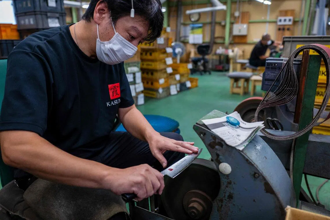 This picture taken on September 2, 2022 shows a worker finishing a knife at a factory of Sumikama Cutlery in Seki, Gifu prefecture. - In a Japanese city once famous for forging samurai swords, craftsmen sharpen and polish kitchen knives, but even at full tilt their small factory can't keep up with global demand. The export value of knives and other bladed tools like scissors hit a record high in Japan last year, partly thanks to a home-cooking boom sparked by the pandemic. (Photo by Kazuhiro NOGI / AFP) / TO GO WITH AFP STORY Japan-lifestyle-culture-craft-knives by Natsuko FUKUE