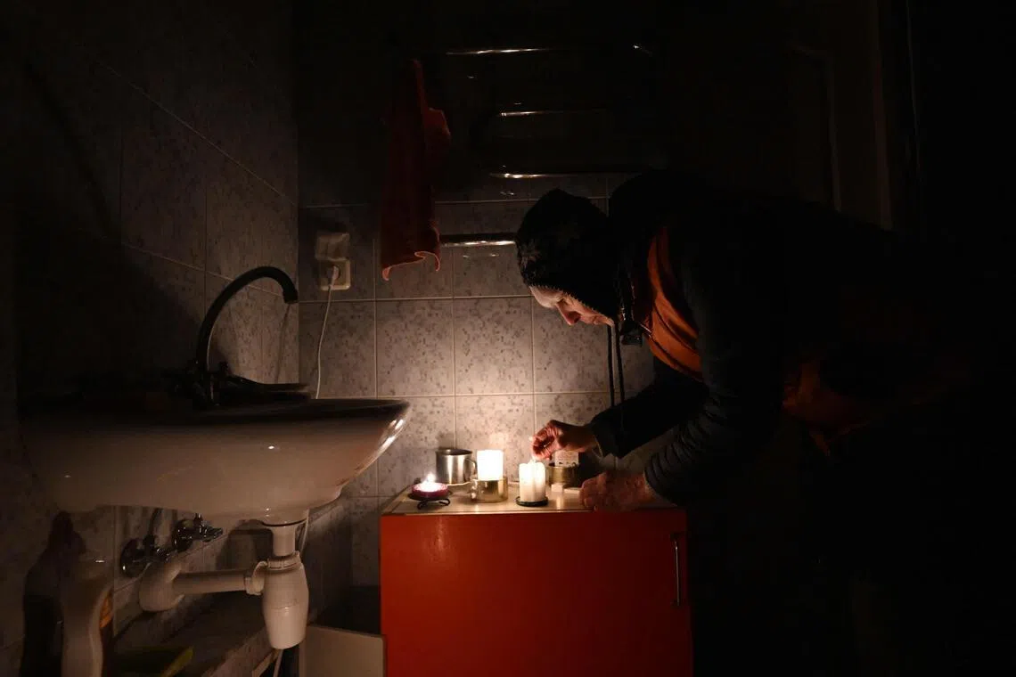 Ukrainian artist Oksana Gordiets, 67, lights candles to heat the bathroom and prevent the water in the pipes from freezing, in Kyiv, on Jan 25.