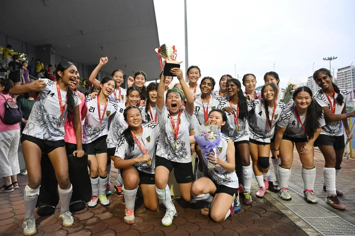 Raffles Institution captain Danica Goh (centre) lifting the trophy after her school's victory over Victoria Junior College in the A Division hockey girls' final. 