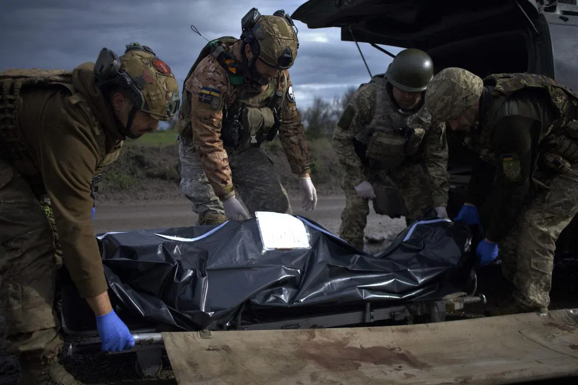 Paramedics load the body of a Ukrainian serviceman into a medical evacuation vehicle near Bakhmut, Donetsk, on April 25.