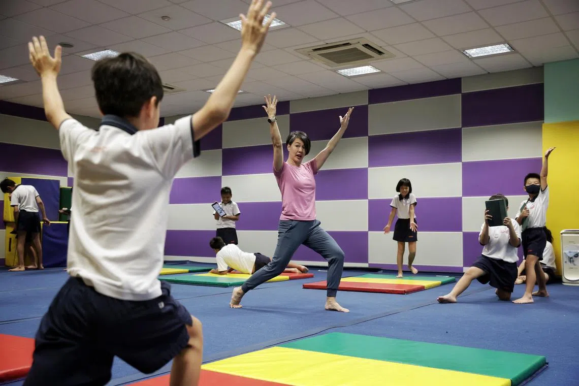 Singapore Physical Education Association Awards winner PE teacher Cassandra Siua refining the end posture of a pupil executing a sequence of movements during a gymnastics class at Cantonment Primary School.