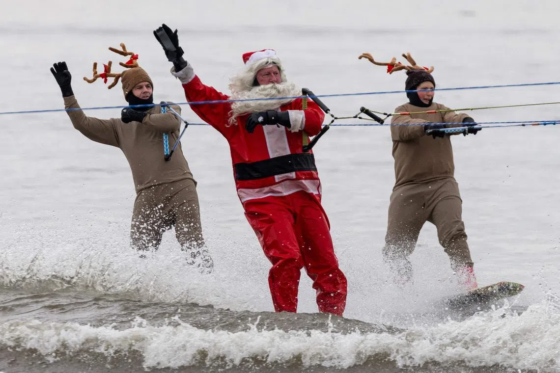 Men dressed as Santa Claus and his reindeer performing during the Water Skiing Santa Show in Alexandria, Virginia, on Dec 24, 2023. 