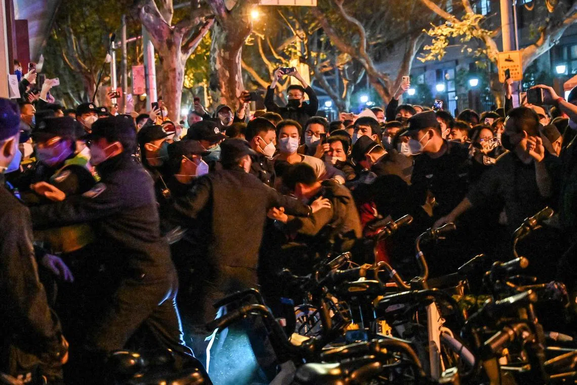 Police and guards arrest a man during clashes in Shanghai on Nov 27, 2022.