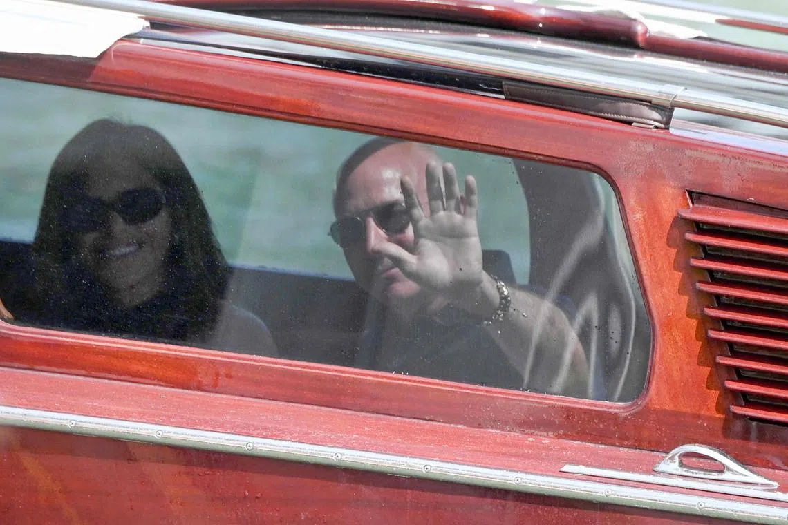 Amazon founder Jeff Bezos and fiancee Lauren Sanchez waving from a river taxi in Venice, as they arrive at historic Italian city's Aman Hotel on June 25.