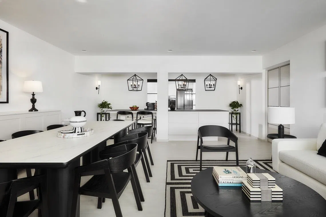 A large striped rug and eight-seater table anchor the living and dining areas of this black-and-white HDB flat.