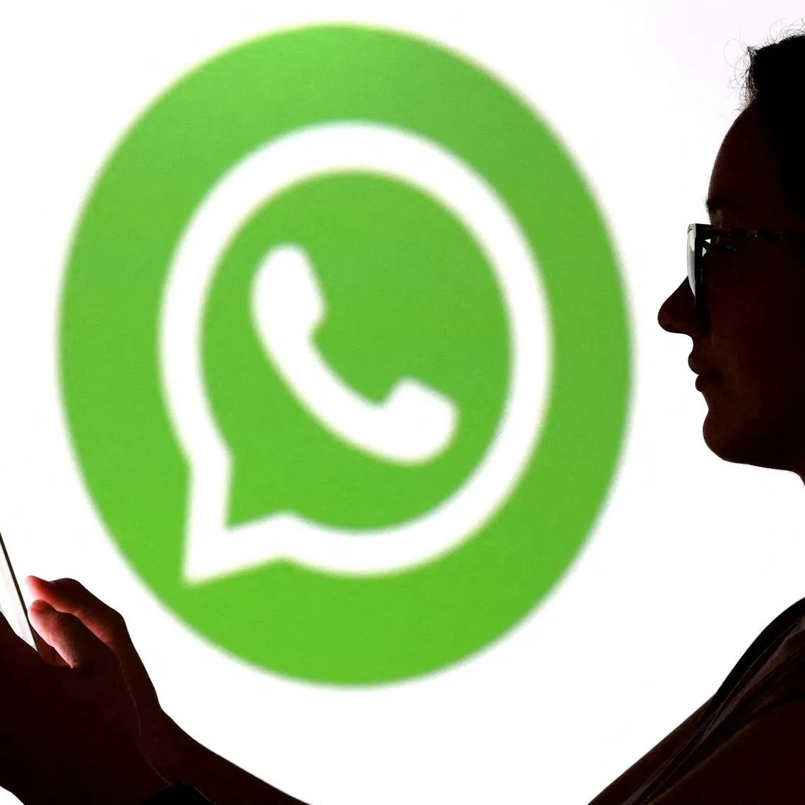 FILE PHOTO: A teenager poses for a photo while holding a smartphone in front of a Whatsapp logo in this illustration taken September 11, 2025. REUTERS/Dado Ruvic/Illustration/File Photo