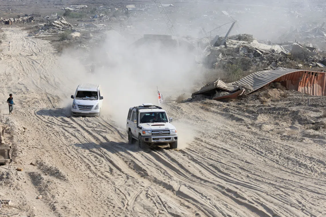 A Red Cross vehicle, escorted by a van driven by a Hamas militant, moves in an area within the so-called \"yellow line\" to which Israeli troops withdrew under the ceasefire, as Hamas says it continues to search for the bodies of deceased hostages seized during the October 7, 2023, attack on Israel, in Gaza City November 12, 2025. REUTERS/Dawoud Abu Alk