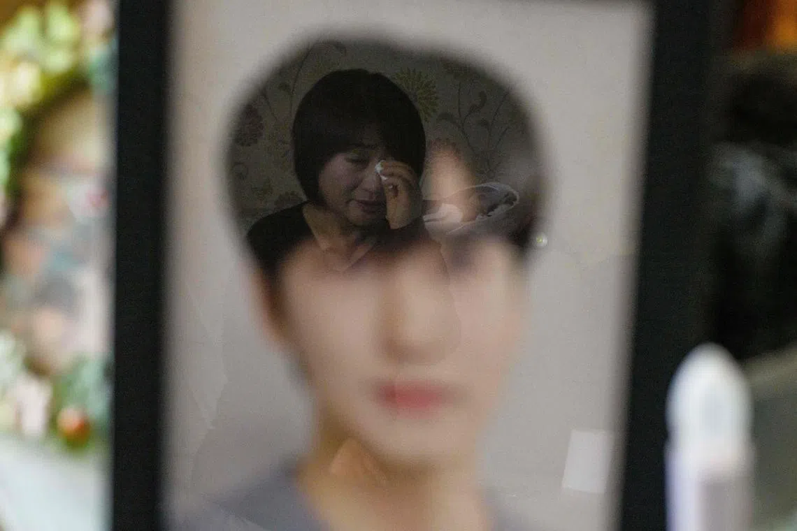 Madam Cho Mi-eun (reflected) whose 24-year-old son Lee Ji-han (foreground in photo) was killed during a Halloween crowd crush in the popular Itaewon district in October last year, crying at their family home in Seoul on March 20. 