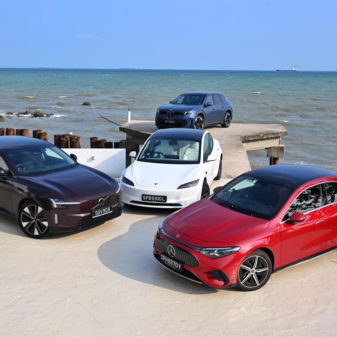 Anti-clockwise from bottom left: The Volvo ES90, Tesla Model 3 Long Range RWD, Mercedes-Benz CLA250+ and BMW iX3 50 xDrive lining up at a disused jetty outside Yard & Co cafe in Pengerang, Malaysia. 