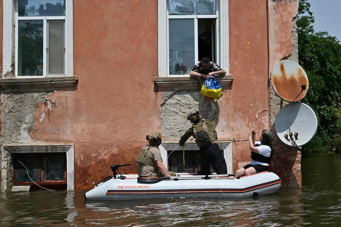 TOPSHOT - Servicemen of the National Guard of Ukraine deliver food to the residents of a flooded area in Kherson on June 8, 2023, following damages sustained at Kakhovka hydroelectric power plant dam. Ukraine and Russia accused each other of shelling in the flood-hit Kherson region on June 8, 2023 even as rescuers raced to save people stranded after the destruction of a Russian-held dam unleashed a torrent of water. (Photo by Genya SAVILOV / AFP)