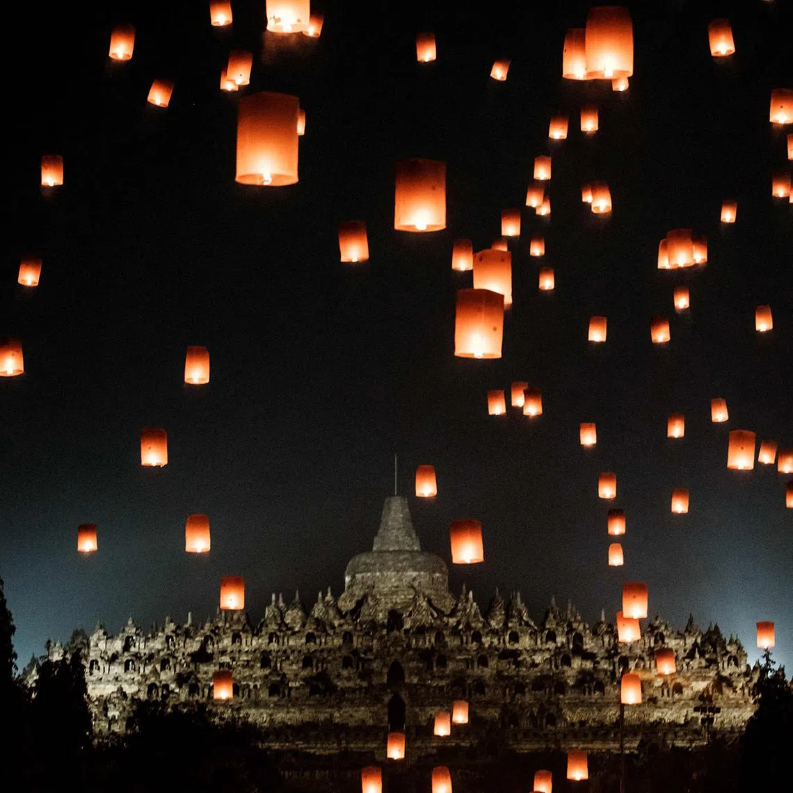 Buddhist devotees releasing lanterns in front of Borobudur Temple, the world's largest Buddhist monument and a UNESCO World Heritage Site, in Magelang, Central Java, on May 12, 2025, as they commemorate Vesak Day. 