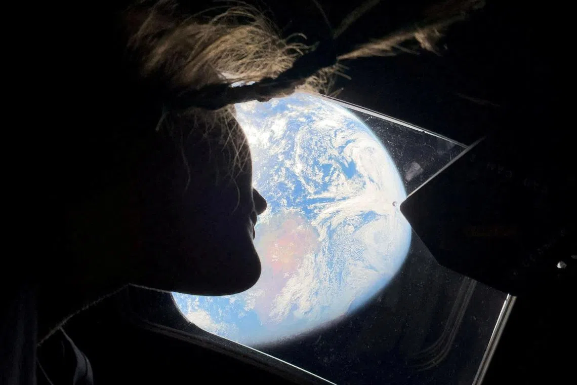 NASA astronaut and Artemis II mission specialist Christina Koch peering out of one of the Orion spacecraft's main cabin windows, looking back at Earth, as the crew travels towards the Moon April 2, 2026.  
