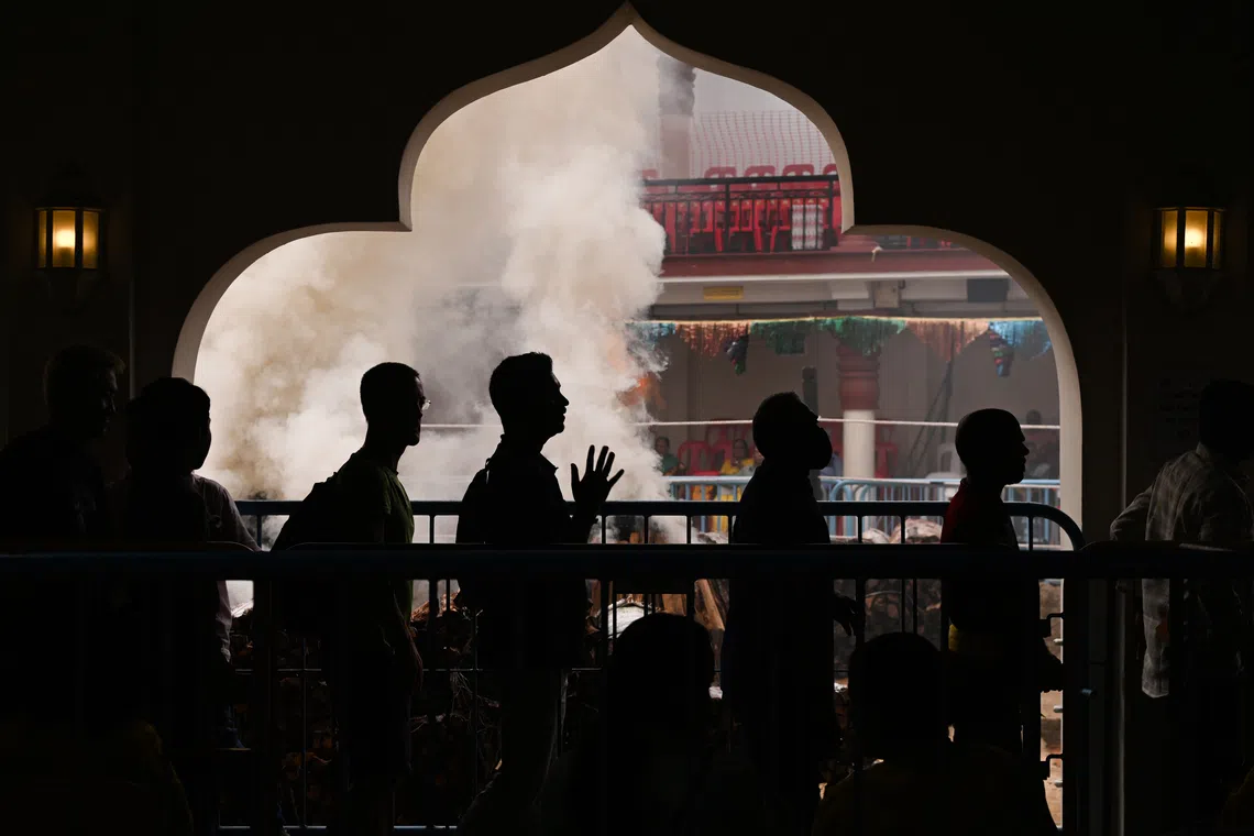 Silhouette of devotees queuing to the sanctum against the thick smoke at Sri Mariamman Temple. 