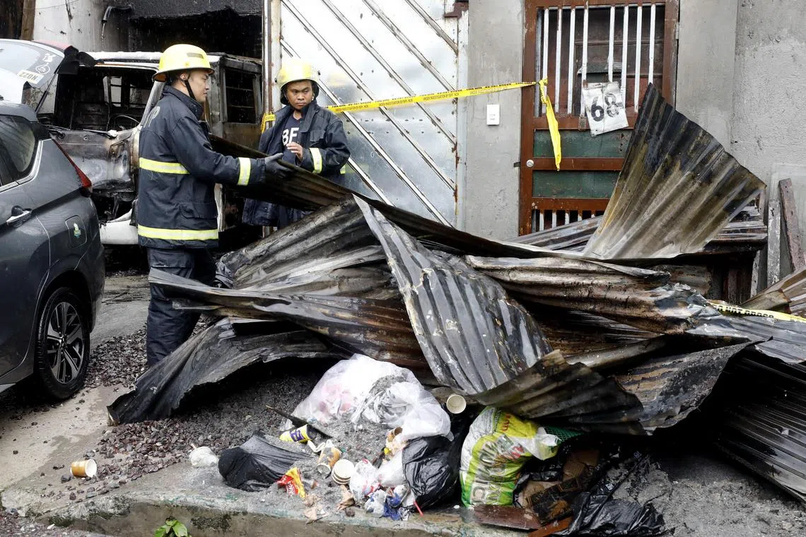 epa10830412 Firefighters set aside burned roofing materials at the site of a fire in a residential village in Quezon City, Metro Manila, Philippines, 31 August 2023. According to the Bureau of Fire Protection, at least 15 people were killed in a fire at a residential area of Quezon City early in the morning of 31 August. Authorities continue their investigation into the fire that broke out inside a house used as a clothing manufacturing facility.  EPA-EFE/ROLEX DELA PENA