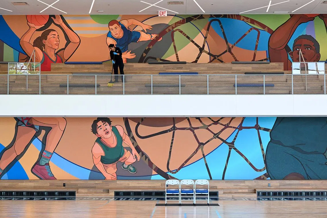 A staff member sweeping the floor in front of a basketball mural at the Home Court building during a media preview of the Obama Presidential Center in Chicago, Illinois, on June 3, 2026, ahead of its grand opening.