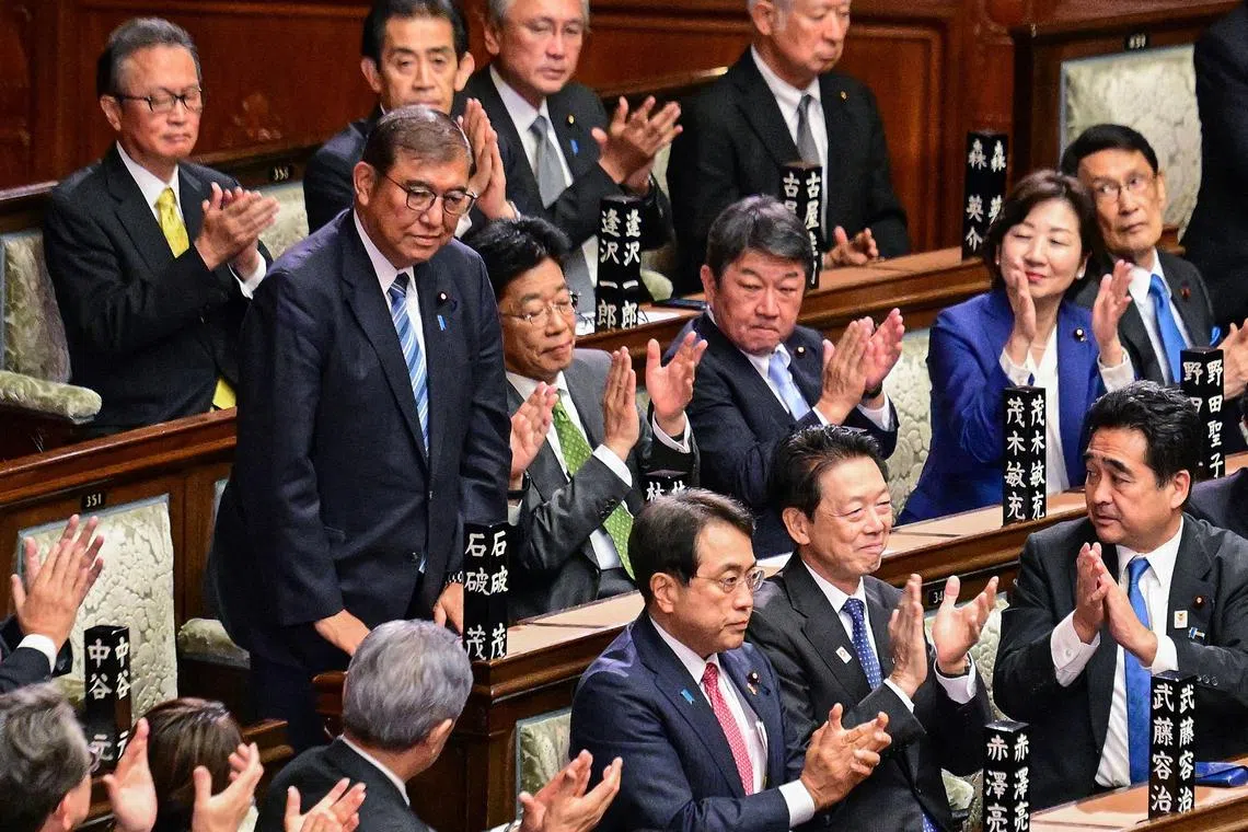 (FILES) This file photo taken on November 11, 2024 shows lawmakers applauding as Japan's Prime Minister Shigeru Ishiba (standing L) is reappointed as leader after the second round of a parliamentary vote to nominate a prime minister following the October 27 general election, during a special session of parliament in Tokyo. Diligent career politician Ishiba, 68, is from Japan's tiny Christian minority and is partial to policy nitty-gritty, model battleships and cigarettes. Seen as safe pair of hands, he became the 10th person since 2000 to lead the LDP on his fifth attempt in September, 2024 promising a "new Japan". (Photo by Yuichi YAMAZAKI / AFP) / TO GO WITH Japan-politics-Ishiba,Q&A by Kyoko HASEGAWA