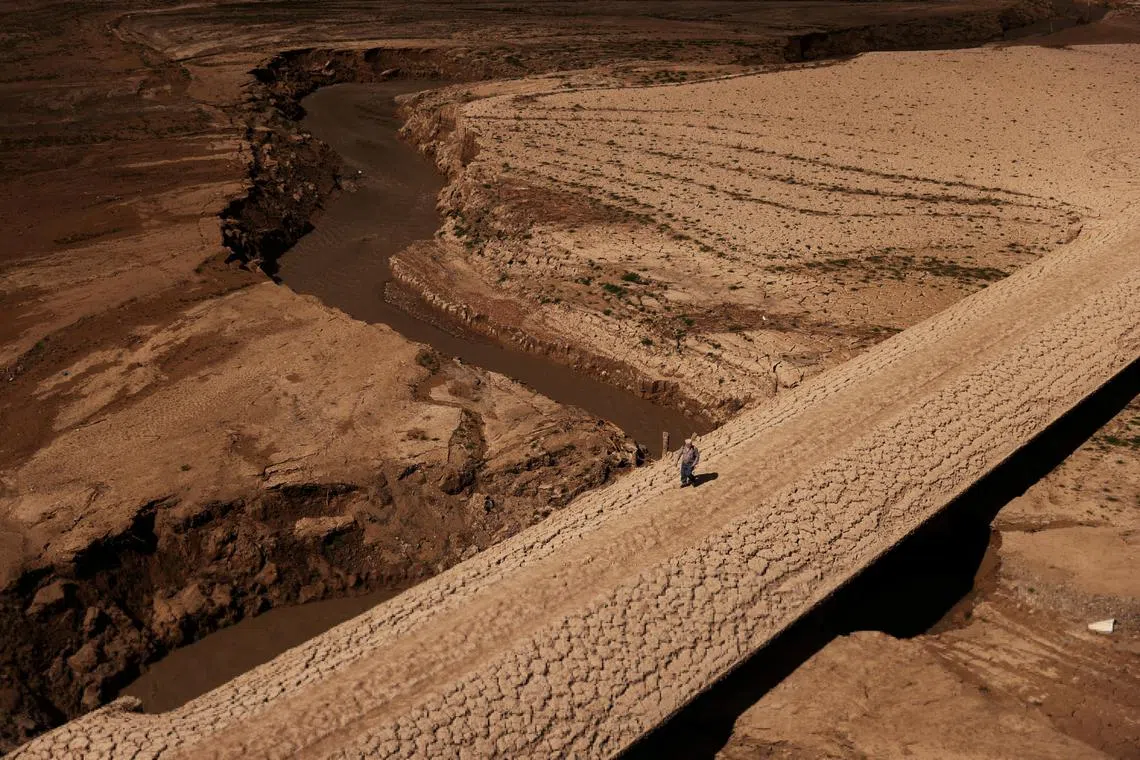 A man walks on the cracked ground of the Baells reservoir amidst extreme drought in Catalonia, Spain, on March 14, 2023. 