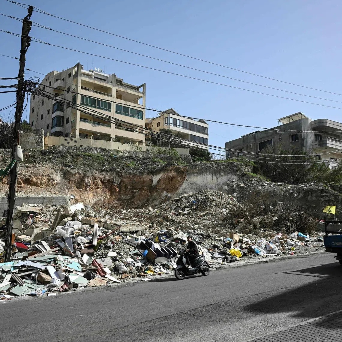 Vehicles drive past the rubble of a building that was hit in January by an Israeli strike in the southern Lebanese village of Qannarit, on Feb 16.