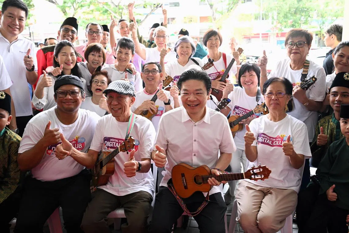 PM Lawrence Wong taking a picture with ukulele players at the inaugural Seniors' Connect at Kovan Hub.