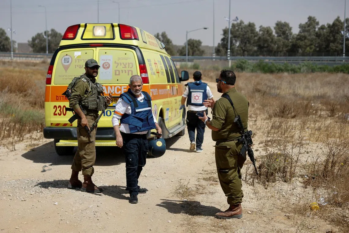 Israeli soldiers and medics walk near an ambulance after Palestinian Islamist group Hamas claimed responsibility for an attack on Kerem Shalom crossing, near Israel's border with Gaza in southern Israel, May 5, 2024. REUTERS/Amir Cohen