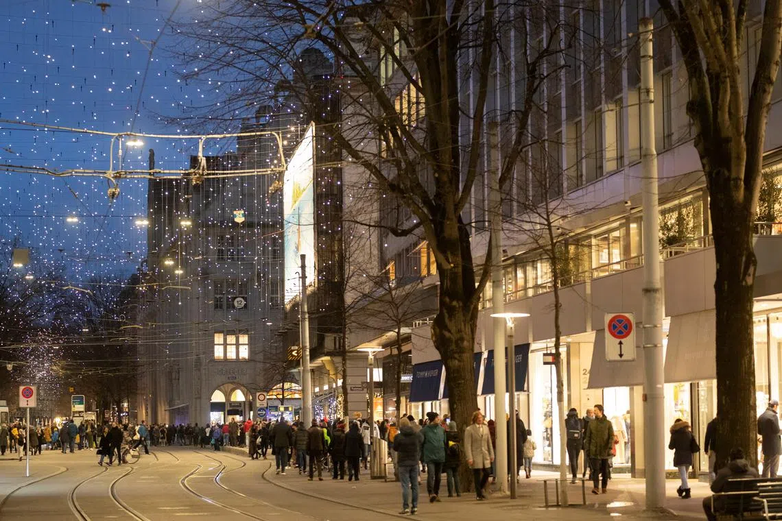 People walk under Christmas illuminations on the Bahnhofstrasse shopping street in Zurich, Switzerland, December 3, 2022. REUTERS/Arnd Wiegmann/ File photo