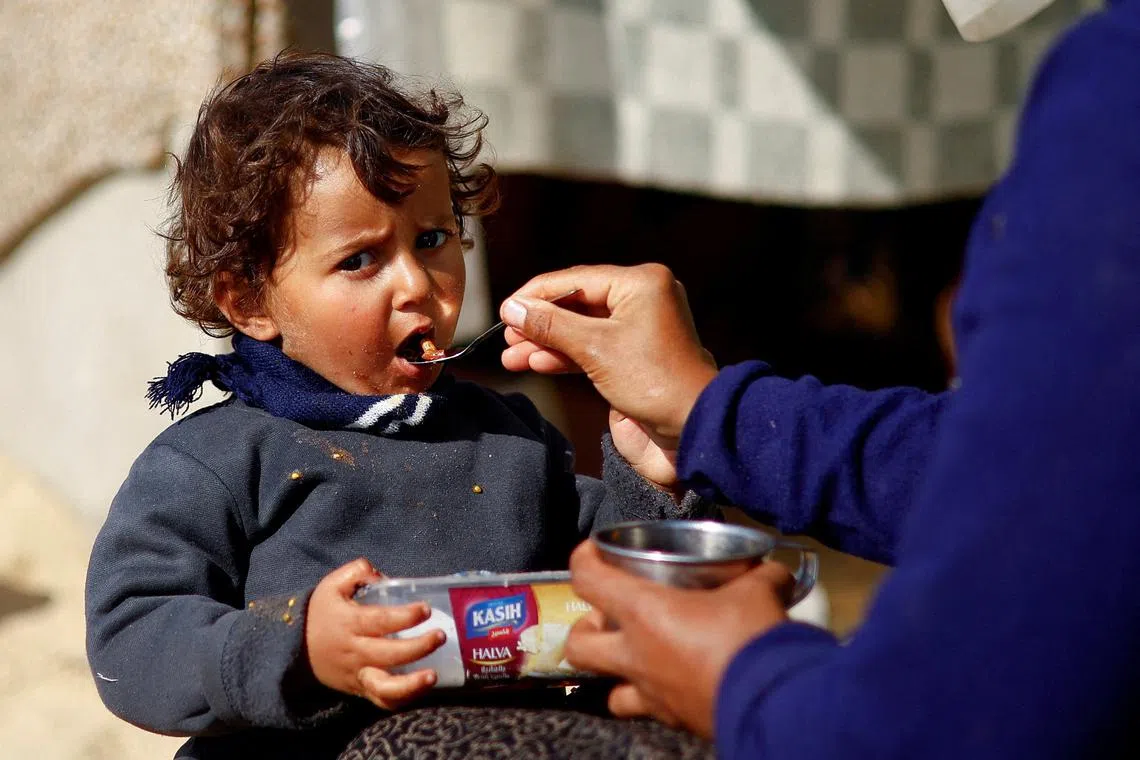 A displaced Palestinian child, who fled due to Israeli strikes, eats, amid the ongoing conflict between Israel and Hamas, in Rafah in the southern Gaza Strip, February 20, 2024. REUTERS/Ibraheem Abu Mustafa