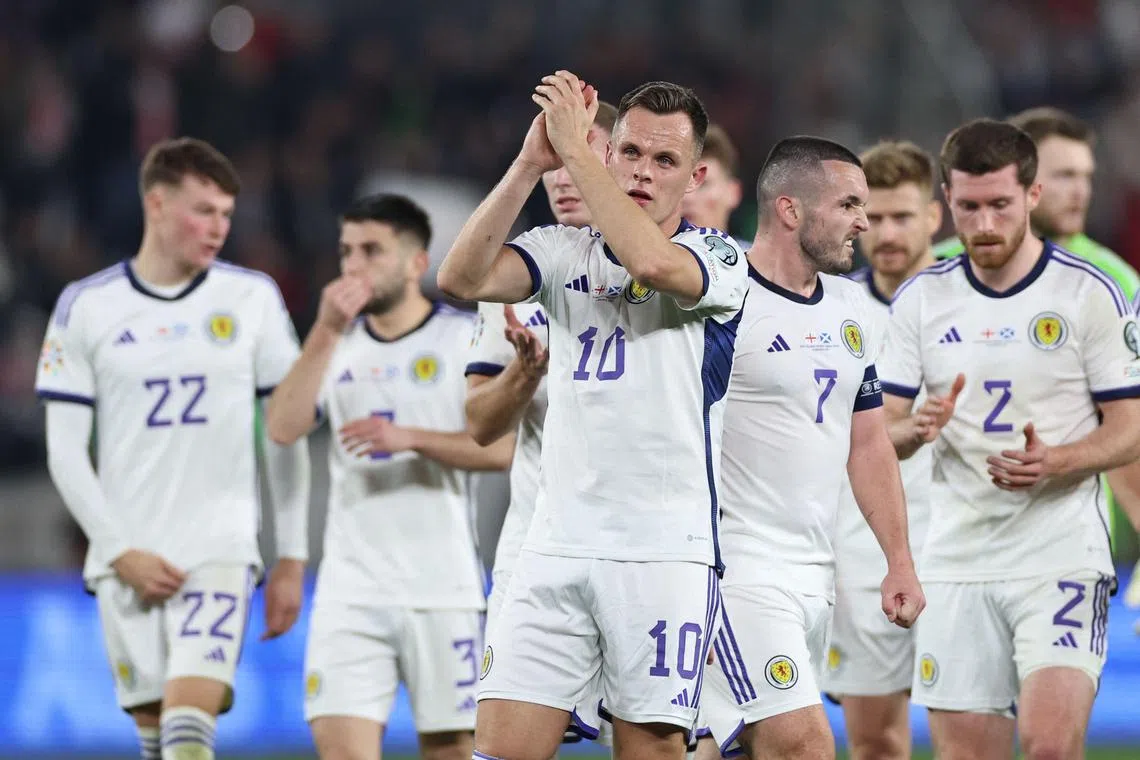 Scotland striker Lawrence Shankland (centre) and teammates applaud supporters after the match.