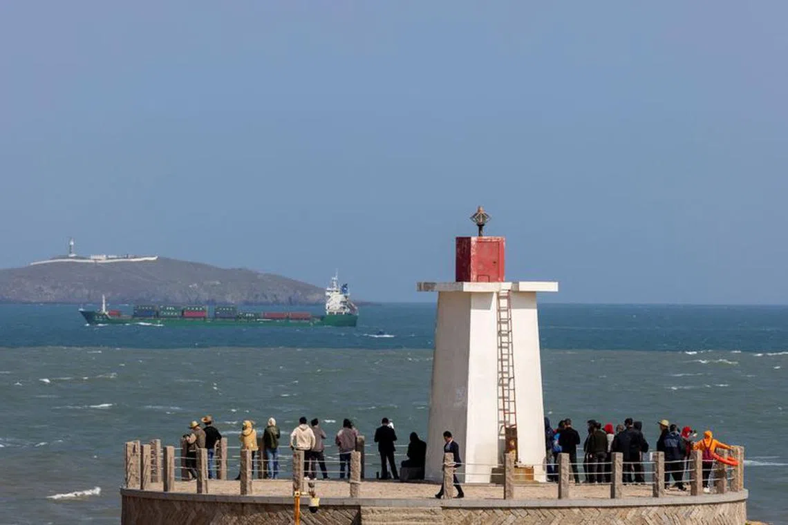 FILE PHOTO: People look across the strait from a lighthouse at the 68-nautical-mile scenic spot, one of mainland China's closest points to the island of Taiwan, on Pingtan Island, Fujian province, China, April 9, 2023. REUTERS/Thomas Peter/File Photo