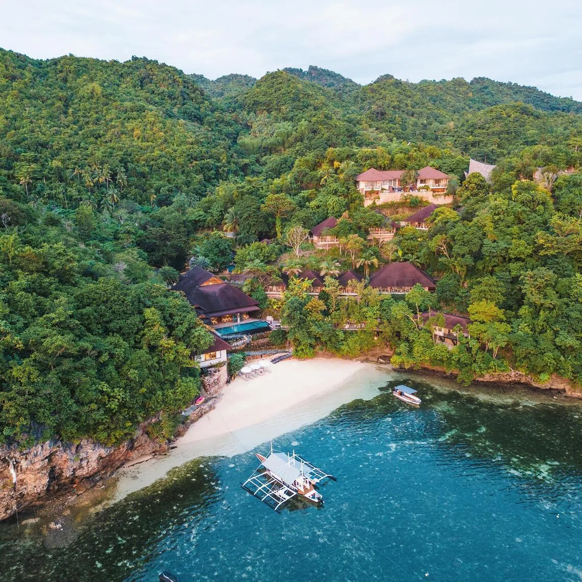 The private beach opens to a grassy seashore at Manami Resort.