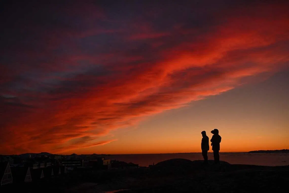 A couple standing on a hill during sunset near the city of Nuuk, western Greenland, on Jan 28, 2026. 