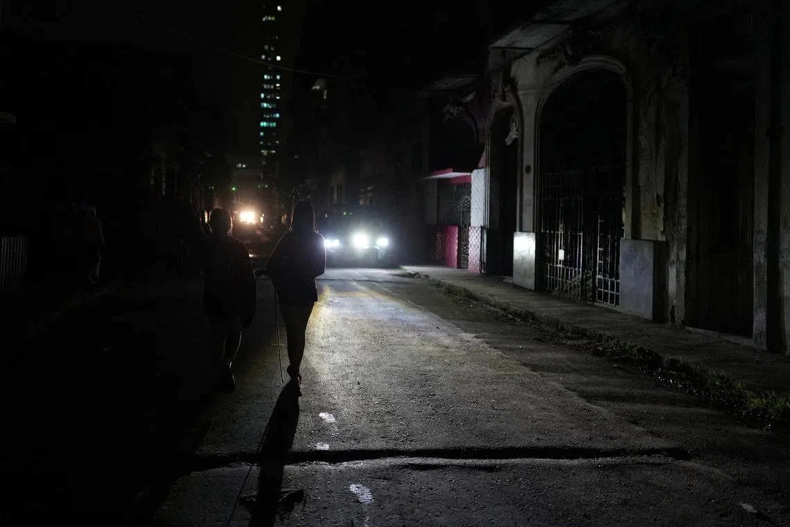 FILE PHOTO: People walk on the street during an electrical grid collapse, in Havana, Cuba, December 4, 2024. REUTERS/Alexandre Meneghini/File Photo