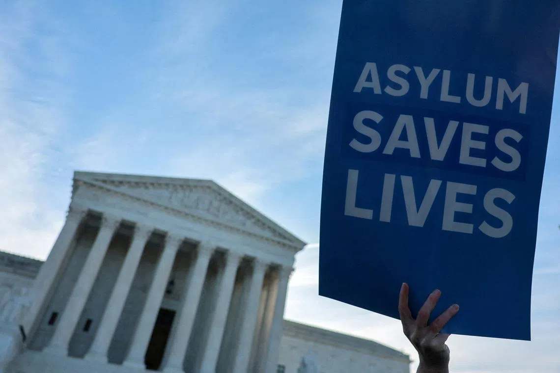 FILE PHOTO: A demonstrator holds a sign as a small group of clergy gather for a vigil prior to arguments in Noem v. Al Otro Lado, a case to determine if noncitizens blocked on the Mexican side of the border by U.S. officials can apply for asylum, at the U.S. Supreme Court building in Washington, D.C., U.S., March 24, 2026. REUTERS/Jonathan Ernst/File Photo