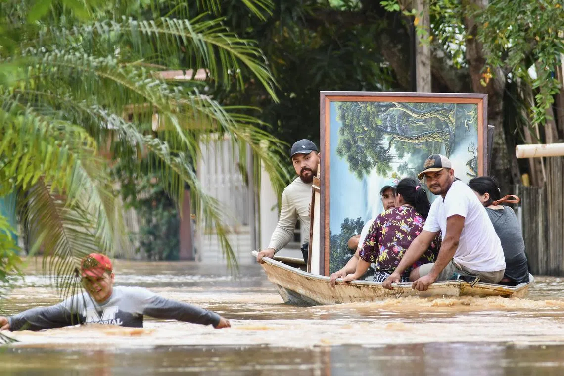 People evacuate their homes after the Acre River overflowed its banks due to heavy rain, in Cobija, Bolivia on Feb 27.