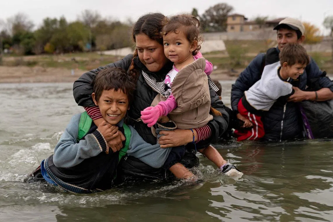 Irma Yolani Cruz, 31, carrying her 1-year-old daughter, Ariana, and her 11-year-old son across the Rio Grande River from Piedras Negras, Coahuila, Mexico, with her husband Jamie Ariel Rapalo, 32, and their other two sons, ages 4 and 8, Dec 21, 2023. 