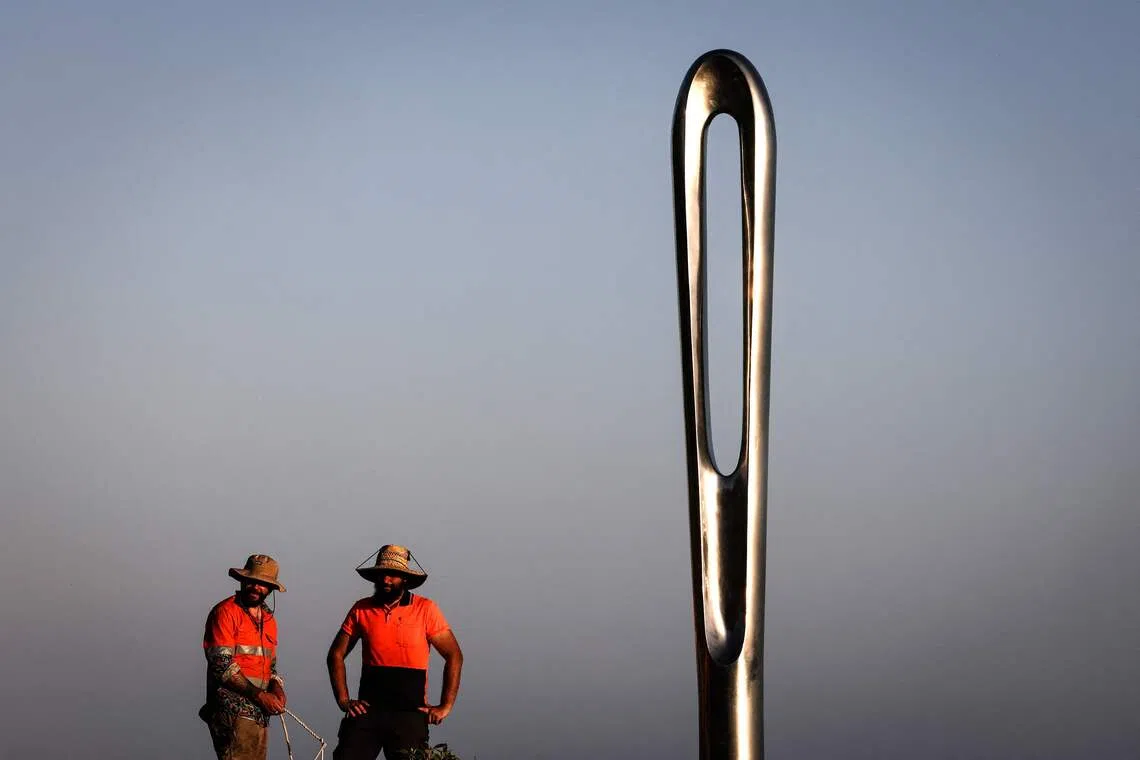 Two workers standing near a work titled ‘Vital Threads’, by Brazilian artist Geraldo Zamproni that is part of the annual Sculpture by the Sea exhibition located near Bondi Beach in Sydney, on Oct 16, 2025. 