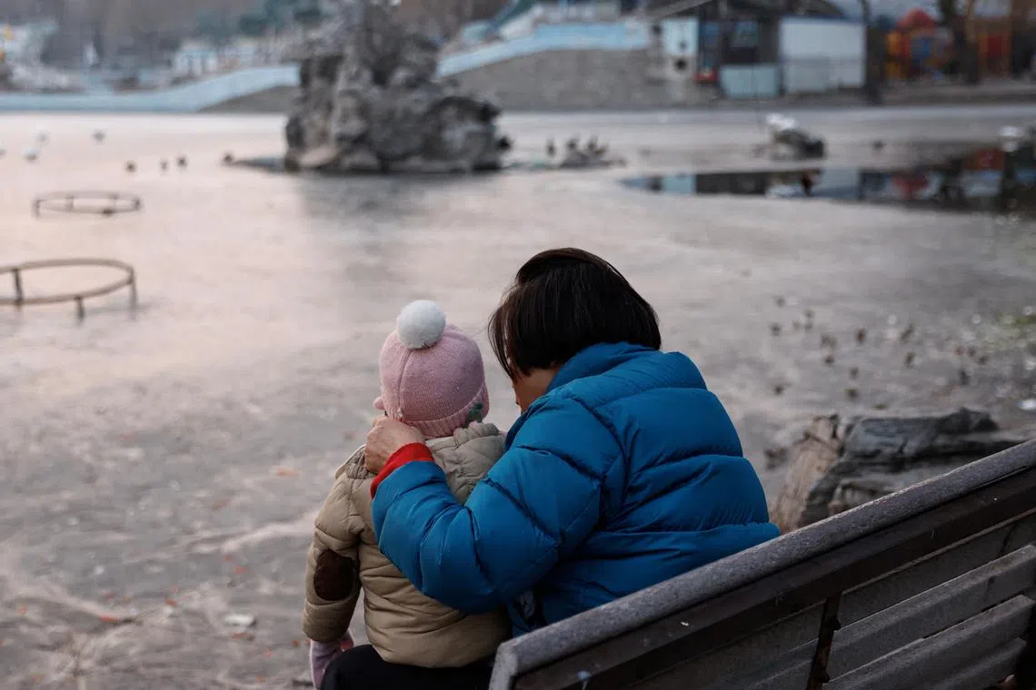 A woman and a child sit in a park in Beijing, China January 12, 2024. REUTERS/Tingshu Wang/ File Photo