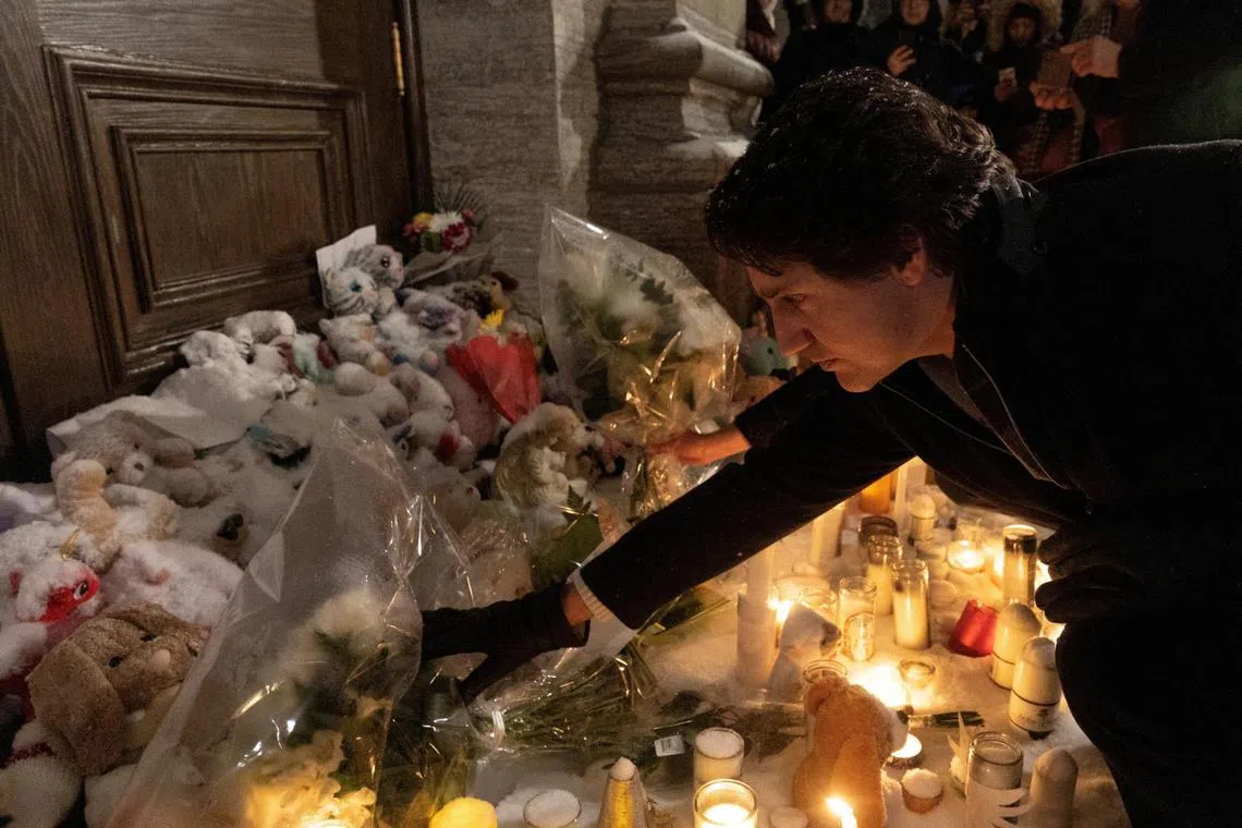 Canada's PM Justin Trudeau lays flowers during a vigil in honour of the daycare bus crash victims, in Quebec on Feb 9, 2023.