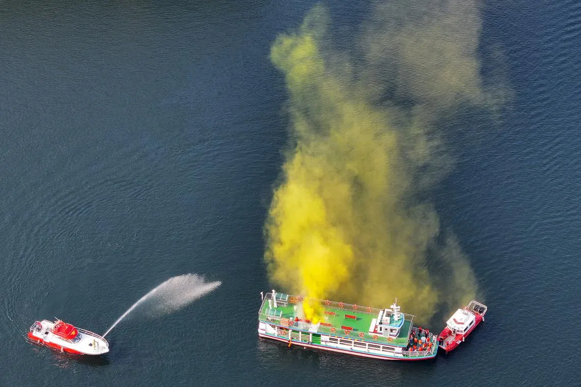 A firefighting service vessel (L) directs water at a pleasure boat on Soyang Lake in Chuncheon, Gangwon Province, northeastern South Korea on October 25, in a drill that simulates a fire on the boat and an oil leak from it.  