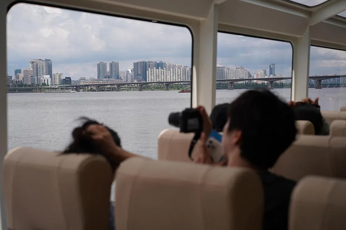 A passenger takes out a camera to take Seoul's cityscape ouside the window of Hangang Bus on July 1, 2025.