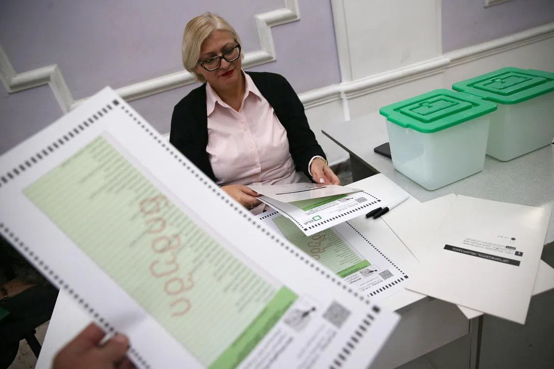 FILE PHOTO: A member of an electoral commission arranges sample ballots at a polling station on the eve of the parliamentary elections in Tbilisi, Georgia October 25, 2024. REUTERS/Irakli Gedenidze/File Photo