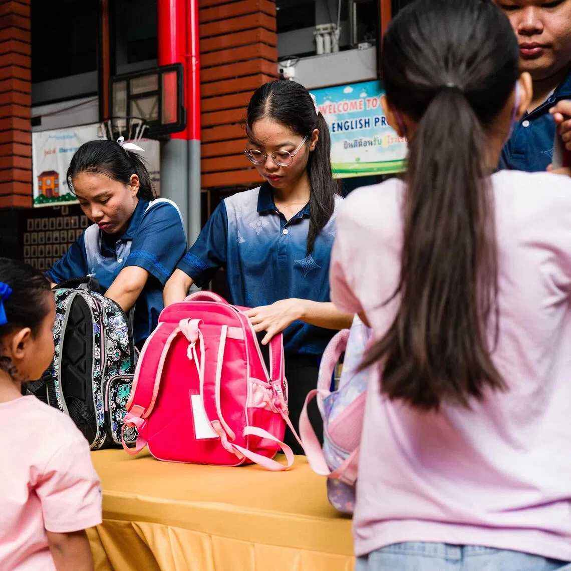 Staff inspecting as students arrive at Sawasdee Wittaya School in Bangkok on Aug 14.