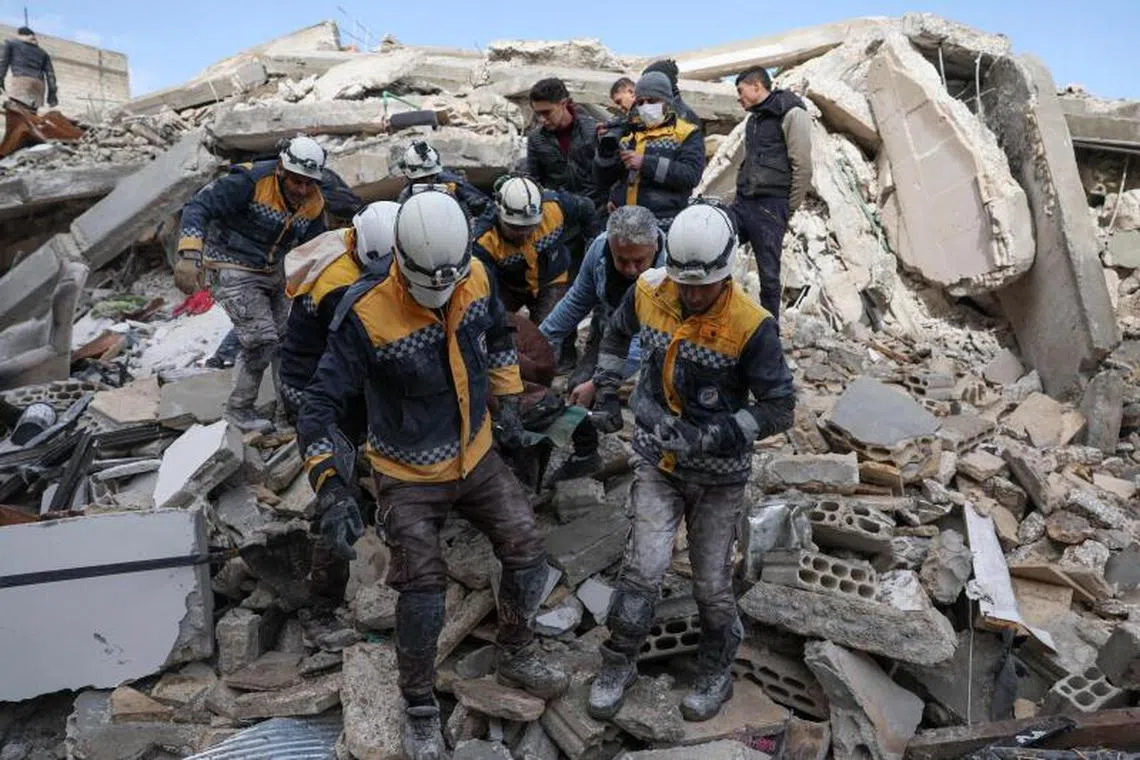 Members of the Syrian civil defence transport a casualty from the rubble of buildings in the village of Azmarin in Syria, on Feb 7, 2023.