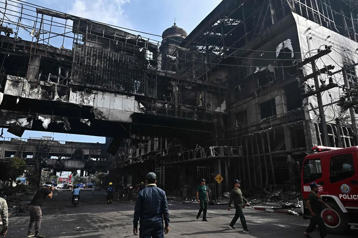 People next to a destroyed part of the Grand Diamond City hotel-casino after a fire in Poipet, on Dec 29, 2022.