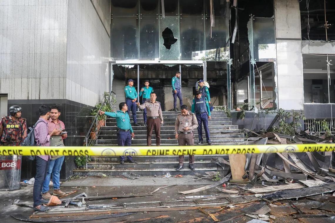 Bangladeshi police stand guard in front of the burnt office of the Daily Star newspaper.