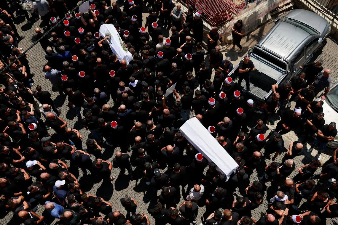 Mourners carry coffins, during the funeral of children who were killed at a soccer pitch by a rocket Israel says was fired from Lebanon, in Majdal Shams, a Druze village in the Israeli-occupied Golan Heights, July 28, 2024. REUTERS/Ammar Awad