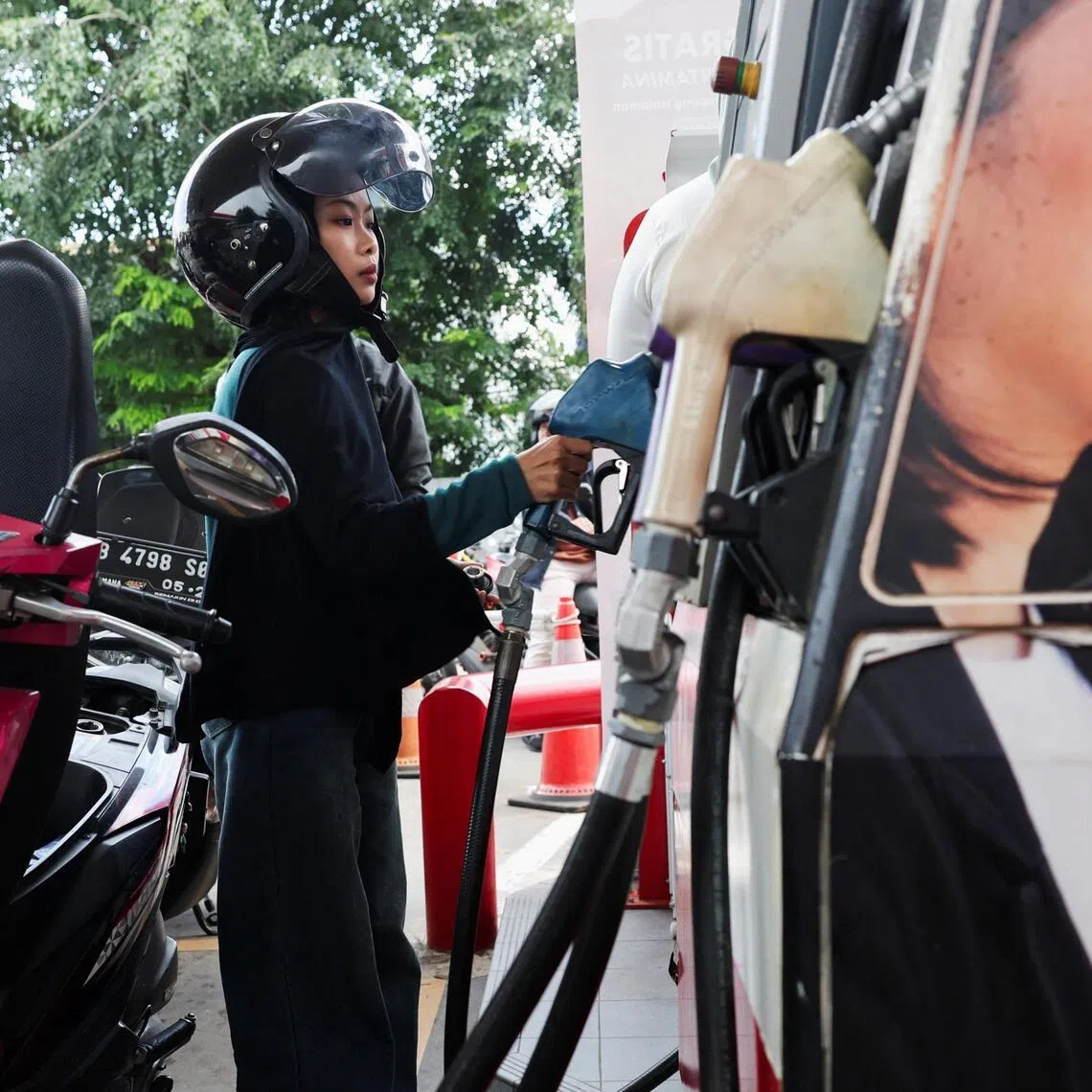 A customer holds a fuel nozzle before filling up a motorcycle at a petrol station of the state-owned company Pertamina in Jakarta, Indonesia, on March 10, 2026.